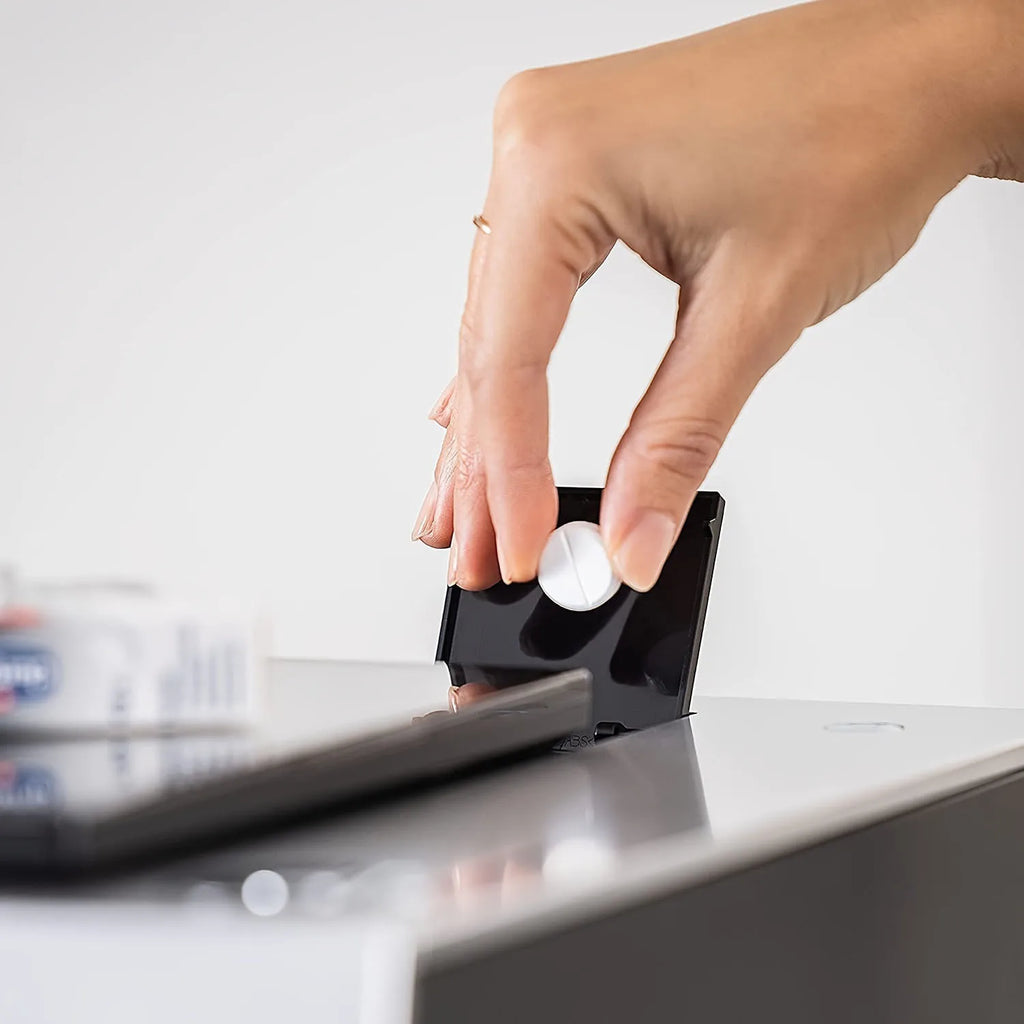 Hand placing a gray cleaning tablet into an espresso machine water reservoir