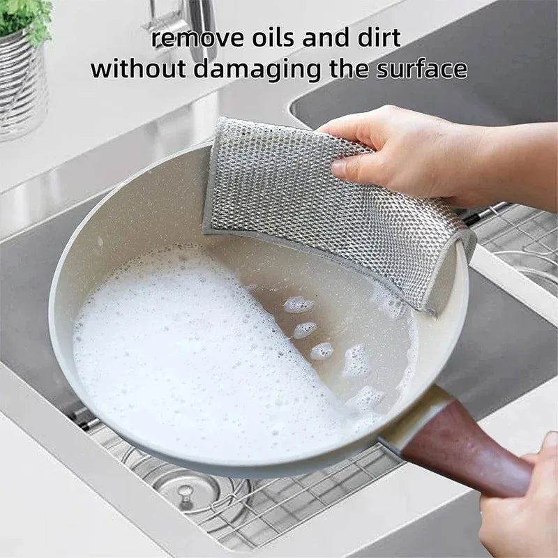 Hand scrubbing with a grey mesh non-scratch cloth in a sink with suds