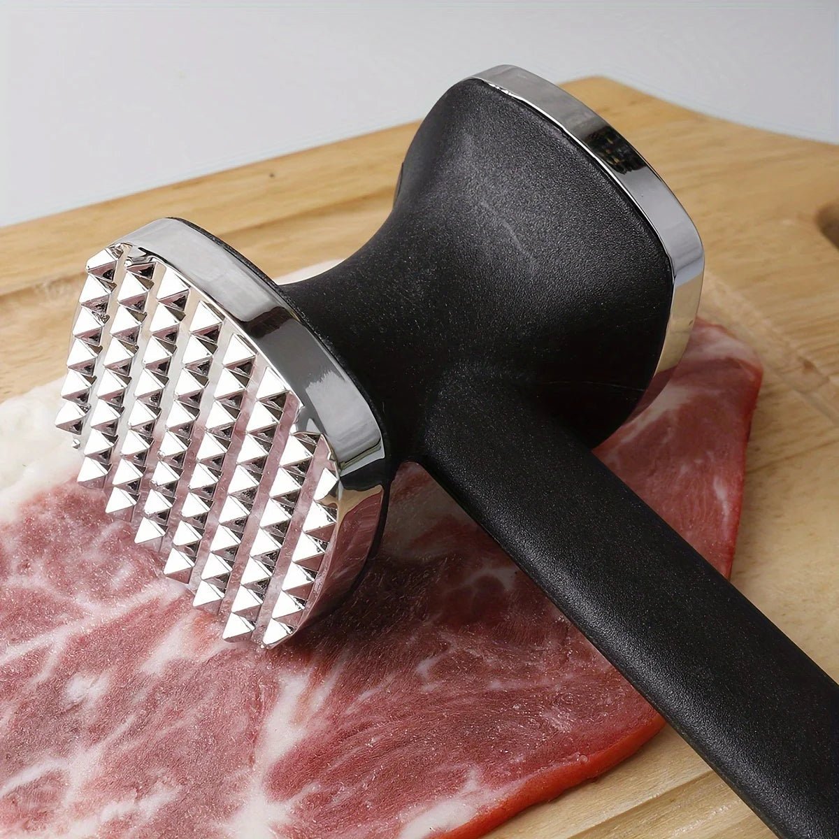 Meat tenderizer mallet head with ribbed metal surface and black handle