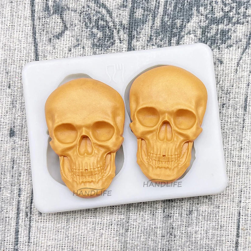 Skull silicone cake mold tray holding two gold skull cakes in molded cavities