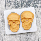 Skull silicone cake mold tray holding two gold skull cakes in molded cavities