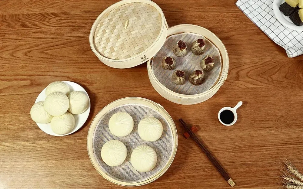 Natural bamboo steamer basket with lid, woven round design, filled with dumplings