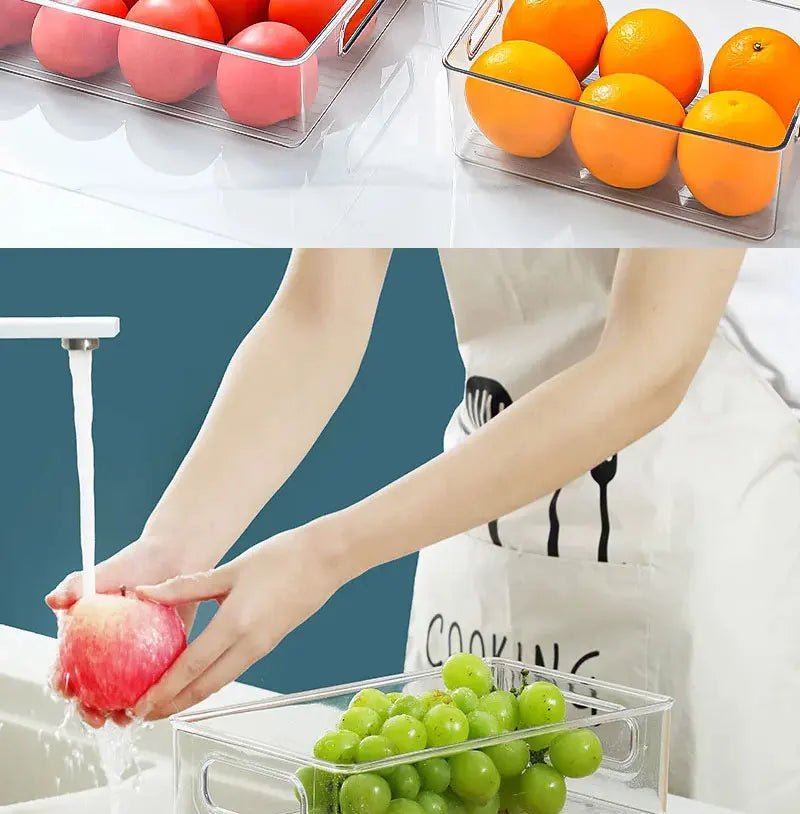 Clear refrigerator storage bin with built-in handles holding grapes, with a hand placing items