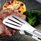 Stainless steel tongs with slotted spatula tip and green silicone grip handle