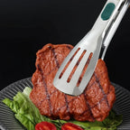 Stainless steel serving tong with slotted spatula head and green silicone handle grip