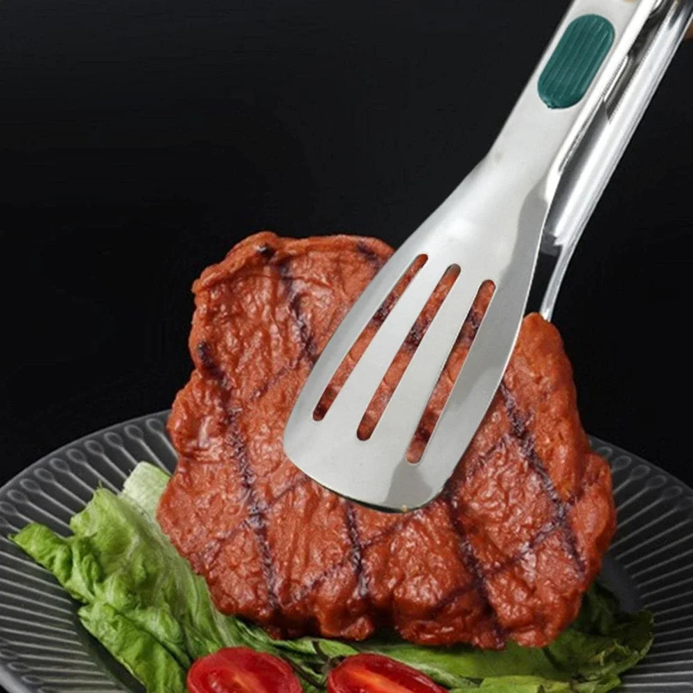 Stainless steel serving tong with slotted spatula head and green silicone handle grip