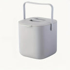 Light gray countertop compost bin with carry handle and vented lid opening