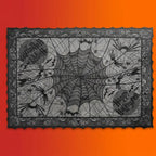 Black lace Halloween tablecloth with spider web pattern, spiders, bats, and Happy Halloween text on orange-red gradient background.