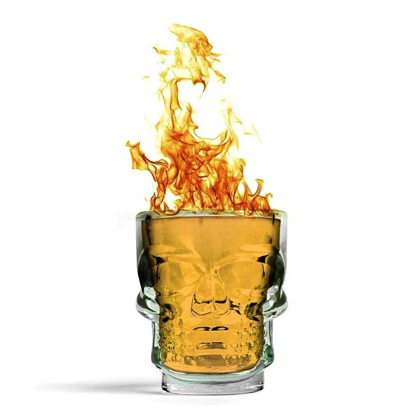 Skull head shot glass with amber drink and flames, clear skull face on front