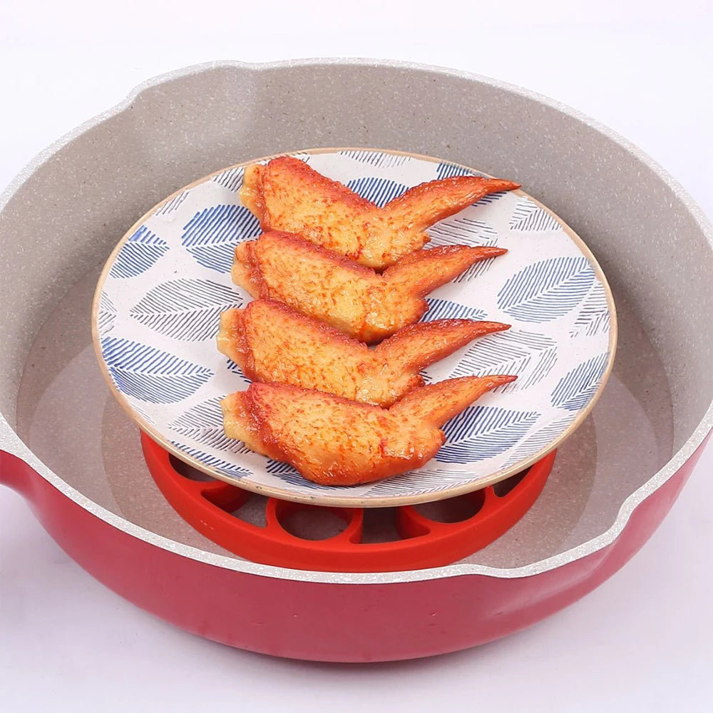 Red silicone egg steamer rack under a plate with cooked shrimp