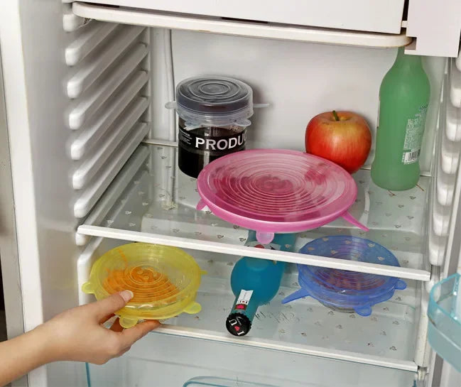 Silicone stretch lids in pink, yellow, and blue on refrigerator shelf