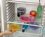 Silicone stretch lids in pink, yellow, and blue on refrigerator shelf