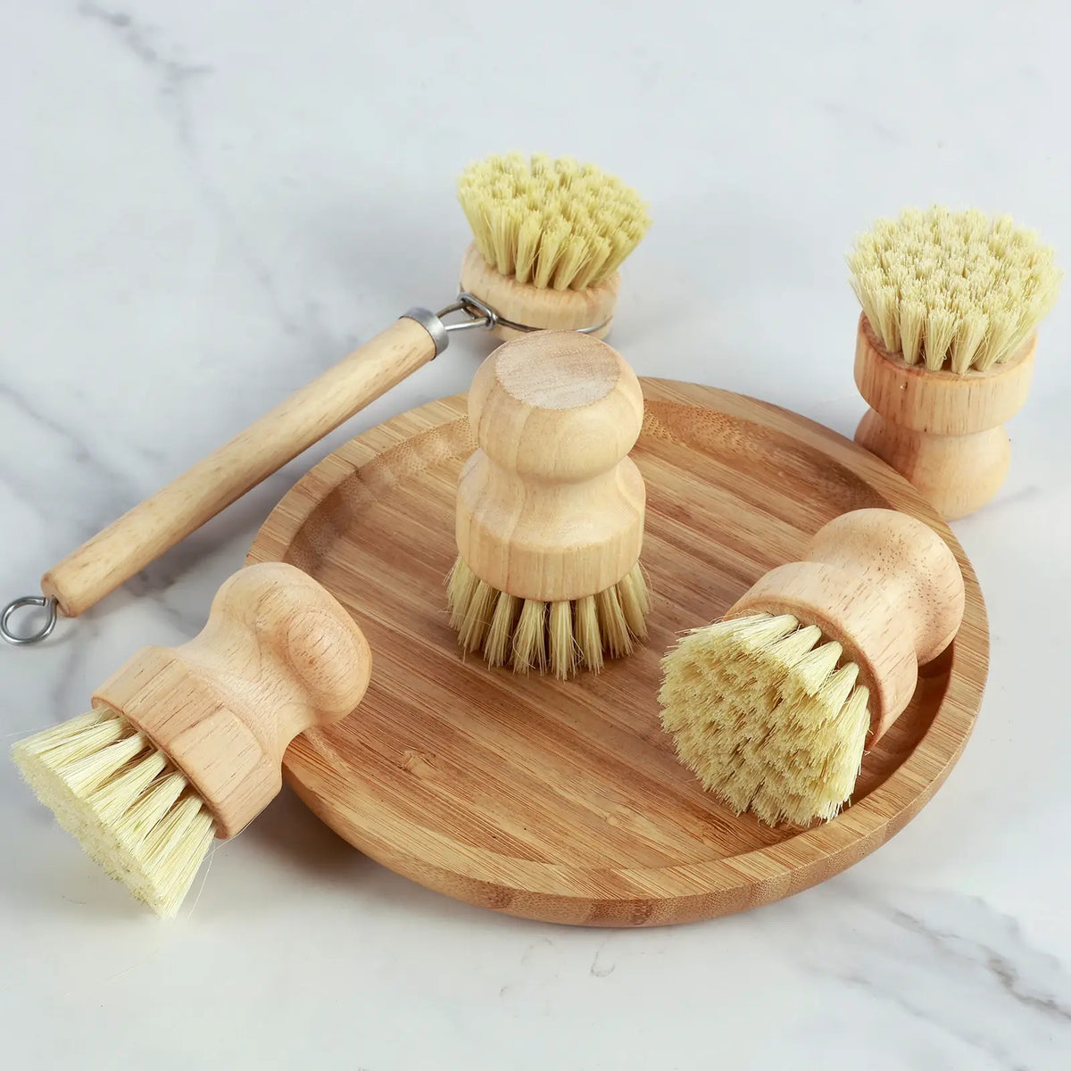 Multiple dish scrub brushes on a round bamboo board, with wooden handles and yellow bristles
