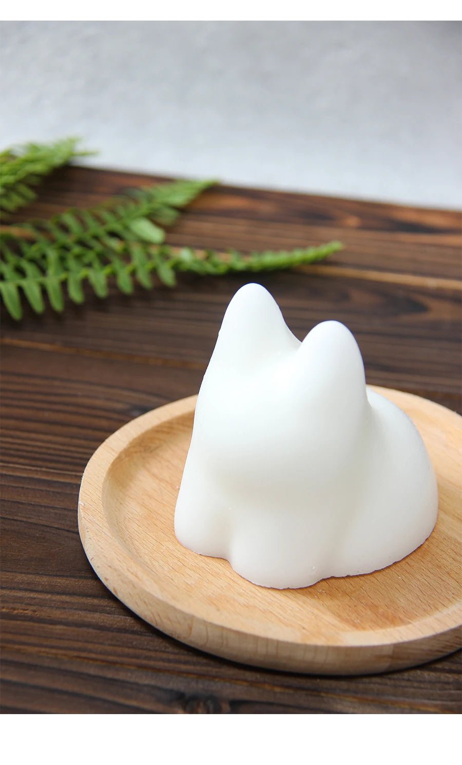 White cat-shaped silicone mold with molded pudding on round wooden plate