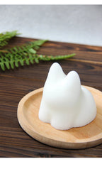 White cat-shaped silicone mold with molded pudding on round wooden plate