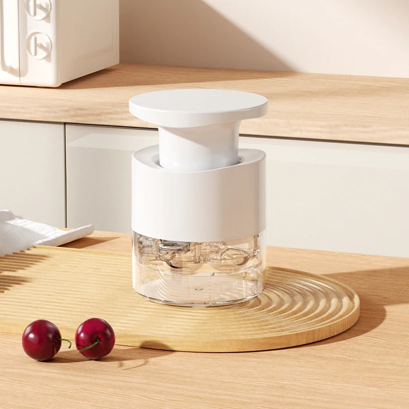 White cherry pitter with white lid and clear chamber; compact kitchen prep tool