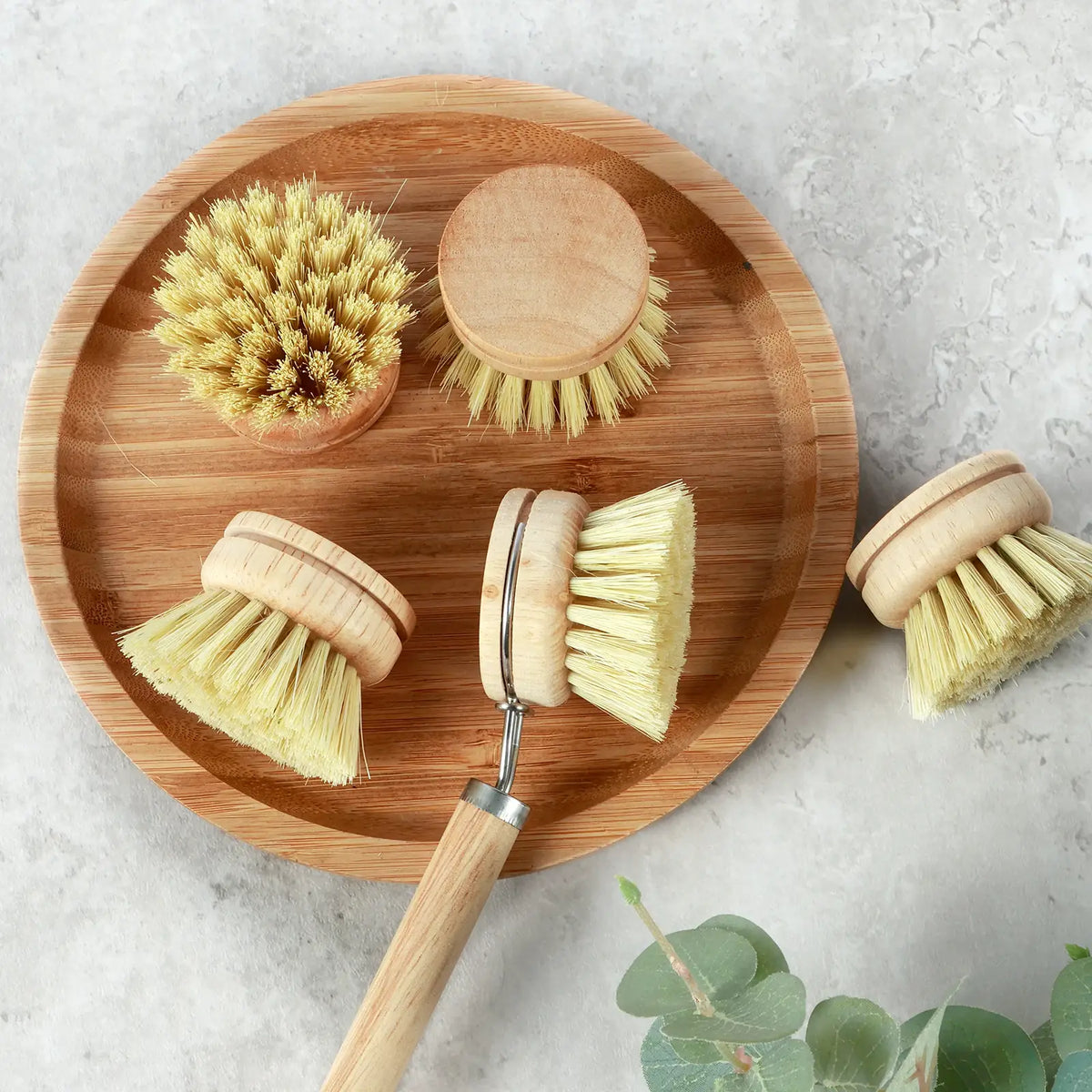 Dish scrub brush set arranged on a round wooden tray