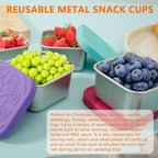 Four small stainless snack cups with colorful silicone lids, filled with fruit
