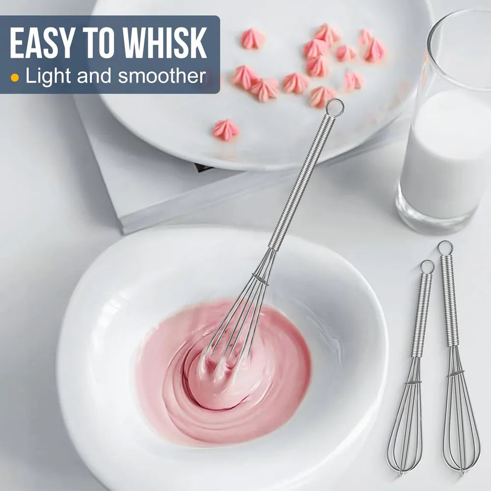 Stainless steel balloon whisk with coil handle and wire head near bowls