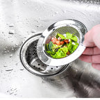 Stainless steel sink strainer basket catching vegetables above kitchen drain