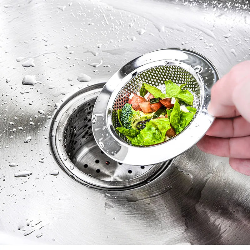 Stainless steel sink strainer basket catching vegetables above kitchen drain