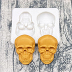 Skull silicone cake mold with two cavities; two gold-colored skull cakes inside