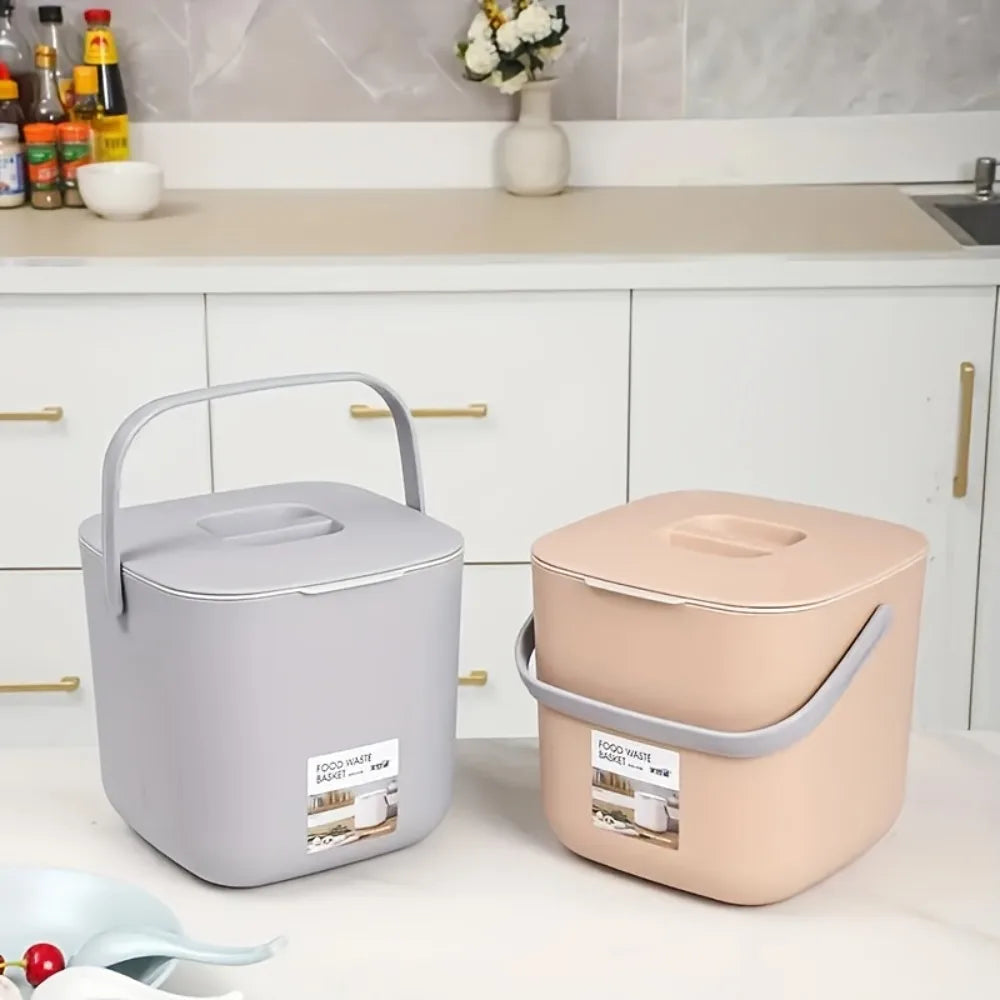Small countertop compost bins in gray and beige with flip-top lids and side handles
