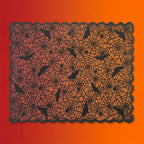 Black lace Halloween tablecloth with spider web pattern, bats, and spiders on orange-red gradient background.