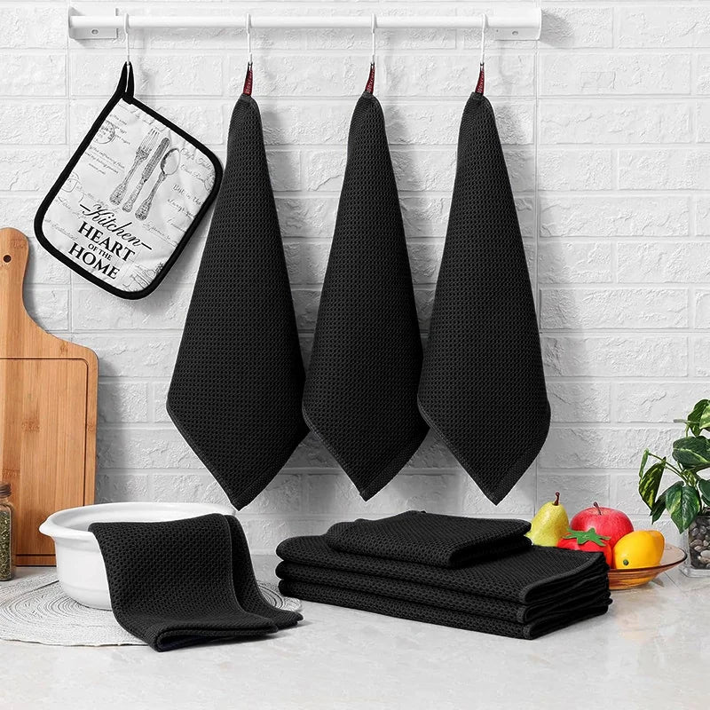 Black waffle weave kitchen towels hanging with folded dishcloth stack