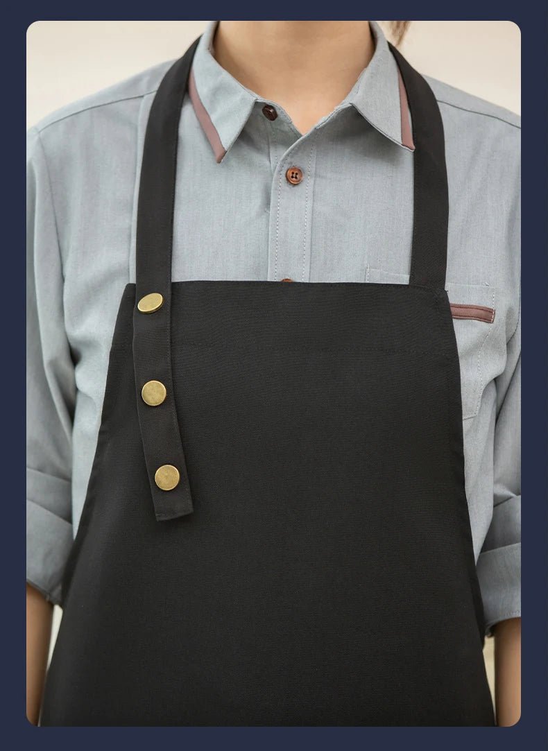 Dark canvas chef apron with brass button strap and front pocket panel