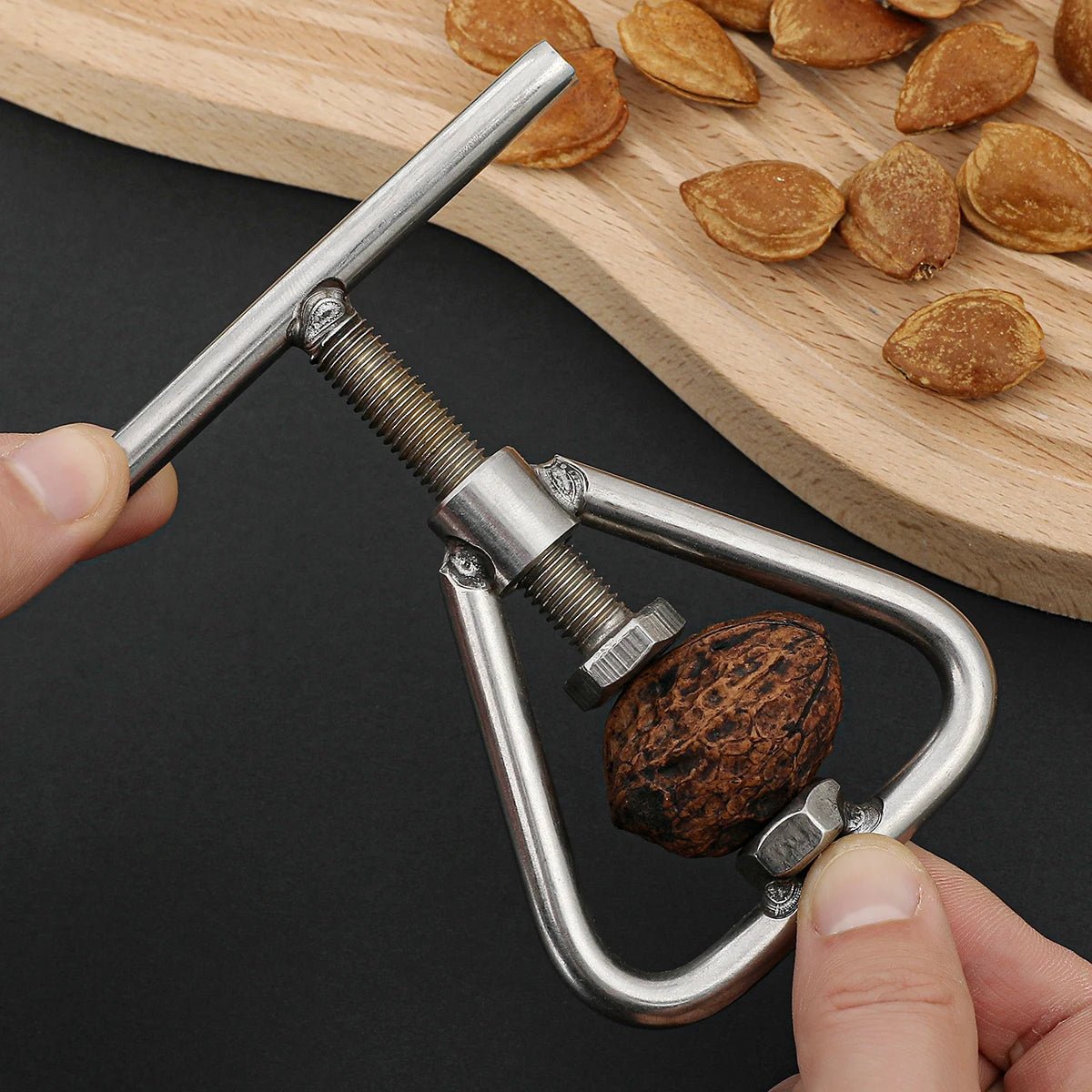 Manual nutcracker and sheller pressing a nut inside the U-shaped metal frame