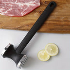 Meat tenderizer mallet on a wooden board with steak and lemon slices