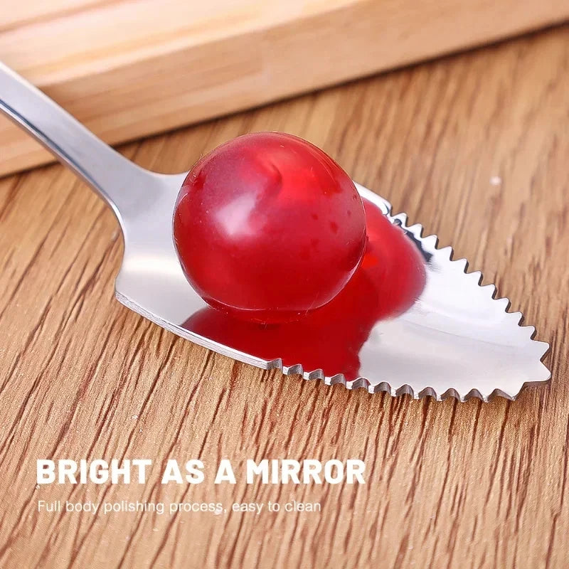 Stainless steel micro-serrated spoon pressing into red fruit on wooden surface