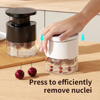 Multi-hole cherry pitter with black lid and clear chamber; hand presses cherries for removal