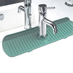 Green silicone faucet splash guard with drain mat ridges beneath chrome faucets