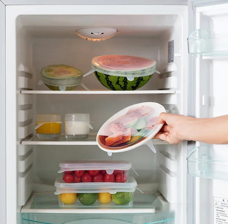 Silicone stretch lids covering bowls in a refrigerator with hands placing a lid