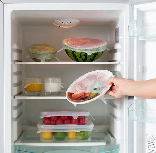 Silicone stretch lids covering bowls in a refrigerator with hands placing a lid
