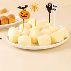 Plastic Halloween cupcake toppers inserted into melon balls with pumpkin, ghost, and bat icons