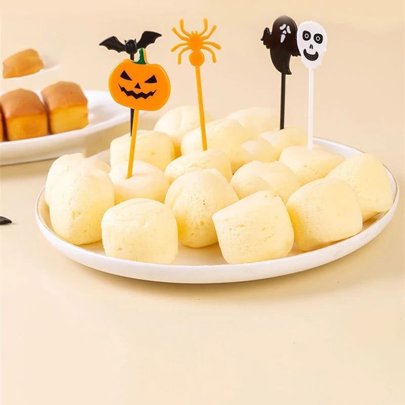 Plastic Halloween cupcake toppers inserted into melon balls with pumpkin, ghost, and bat icons