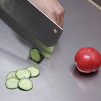 Stainless steel cutting board with sliced cucumber and whole tomato