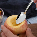 Stainless steel citrus spoon with micro-serrated edge scraping grapefruit