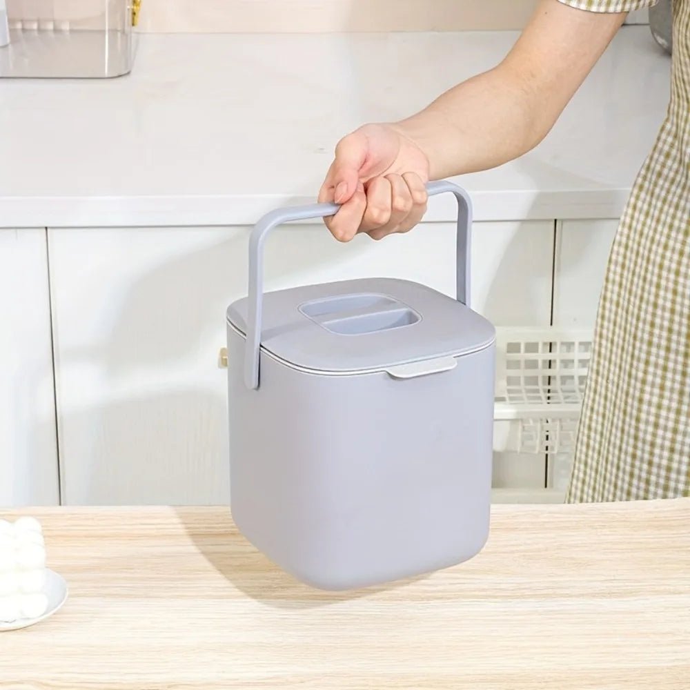 Gray countertop compost bin on kitchen counter with top handle and closed lid