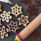 Adjustable beech wood rolling pin beside decorated cookies on a baking grid
