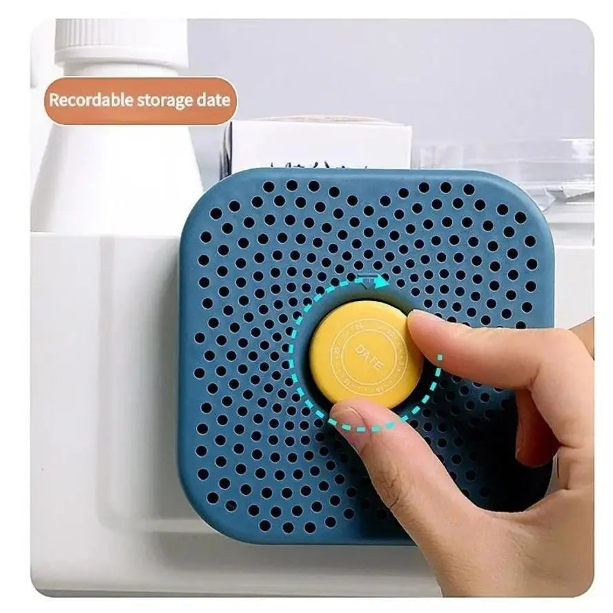 Blue refrigerator deodorizer box with perforated face and yellow date cap being pressed