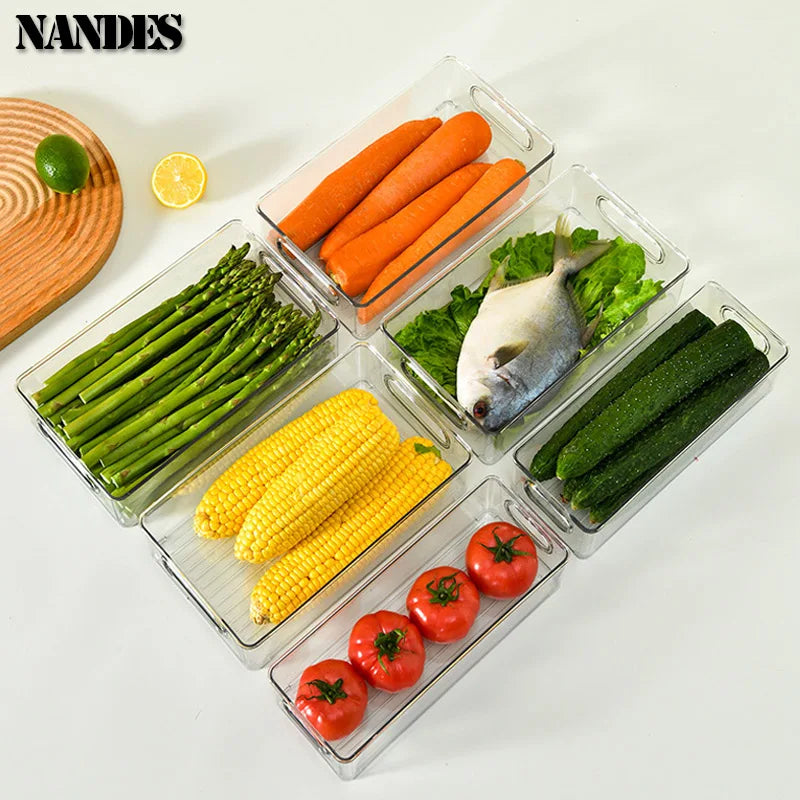 Clear pantry organizer bins with built-in handles holding carrots, corn, and greens