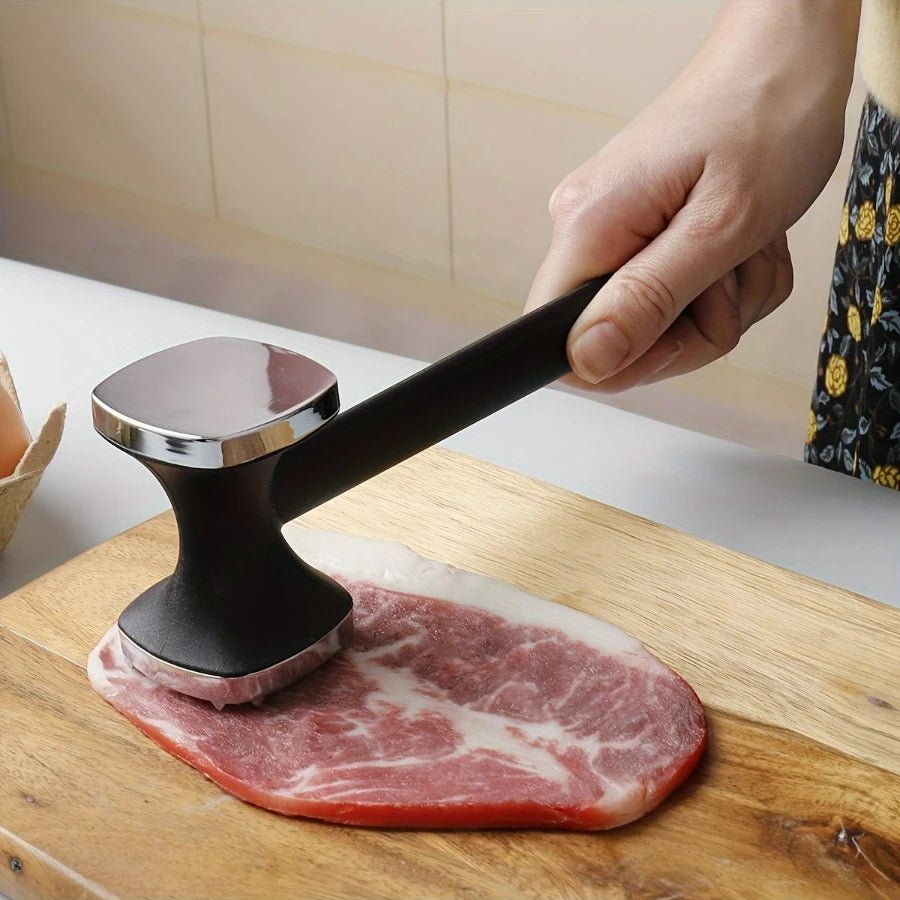 Meat tenderizer mallet with black handle pressing steak on a cutting board