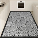 PVC kitchen floor mat with gray-and-white floral damask pattern and black border.