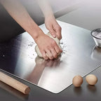 Stainless steel pastry and cutting board being washed, hands scrubbing surface