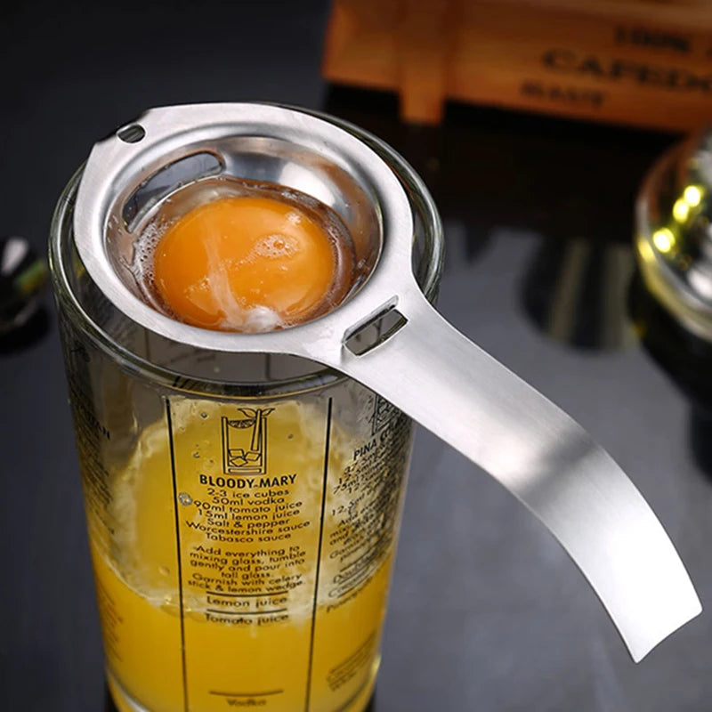 Stainless steel egg separator resting on container, yolk in metal cup