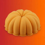 Orange pumpkin-shaped silicone bundt cake or jello mold on orange-red gradient background.